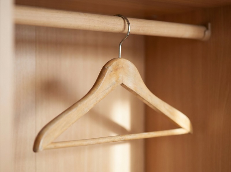 A natural wooden hanger on a wardrobe rail.